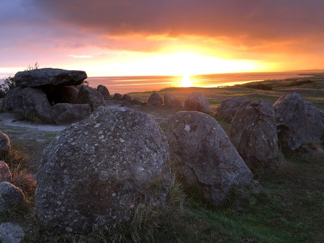 Ancient stone chamber silhouetted against a glowing coastal sunrise